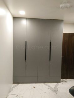 an empty room with two gray cabinets and a black chair in front of the doors