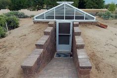 a small greenhouse in the middle of a dirt field with steps leading up to it