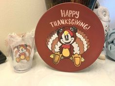 a happy thanksgiving turkey plate sitting on top of a counter next to a glass cup