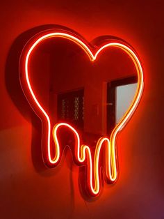 a heart shaped neon sign hanging from the side of a wall next to a mirror