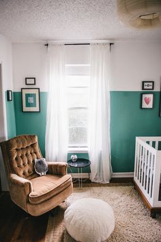 a baby's room with a brown chair and white crib in the corner