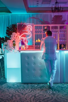 a man standing in front of a bar with neon lights on the wall behind him