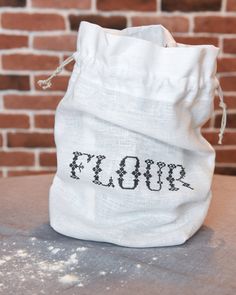 a white bag with the word floss on it sitting on a table next to a brick wall