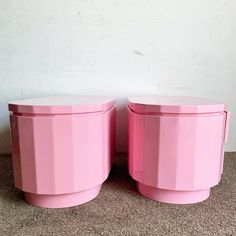 two pink plastic containers sitting next to each other on the floor in front of a white wall