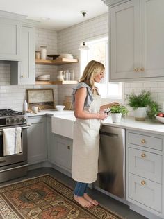 a woman standing in a kitchen preparing food on a counter top next to an oven