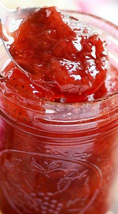 a spoon full of strawberry jam on top of a table