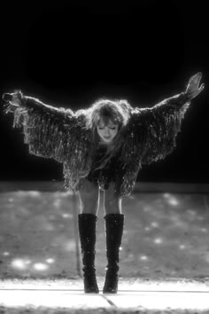 a woman with her arms spread out in the air while standing on top of a stage