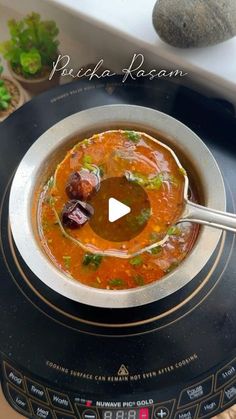 a bowl of soup sitting on top of an electric stove with a spoon in it