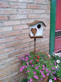 a bird house sitting on top of a planter filled with flowers