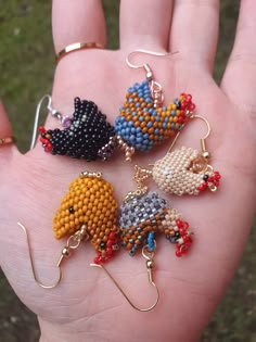 a hand is holding five different beaded animal earrings in it's palm,