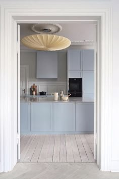 an open door leading to a kitchen with blue cabinets and counter tops, along with a white wooden floor