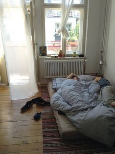 a person laying on top of a bed in a room next to a radiator