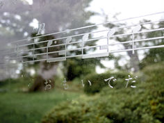 an image of musical notes on the glass window with trees in the back ground and grass behind it