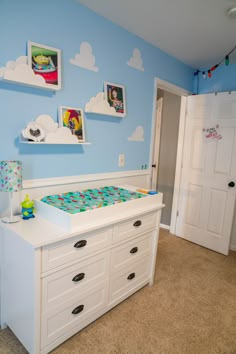 a baby's room is decorated in blue and white with clouds on the wall