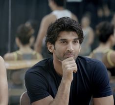 a man sitting at a table with his hand on his chin looking to the side