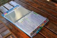 an open book sitting on top of a wooden table next to a dog laying in the grass