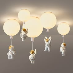 an astronaut themed ceiling light fixture with five lights attached to it, and three astronauts on each lamp