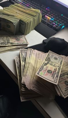 stacks of money sitting on top of a desk next to a computer keyboard and mouse