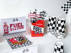 a table topped with black and white checkered paper cups next to boxes of fuel station