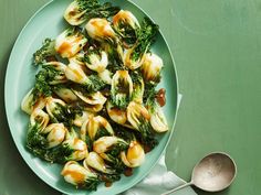 a plate full of pasta and broccoli on a green tablecloth next to a spoon