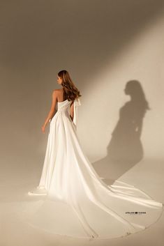 a woman in a white dress is standing with her back to the camera