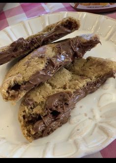 two chocolate chip cookies on a plate with a pink tablecloth and checkered table cloth