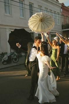 a bride and groom dancing in the street with umbrellas