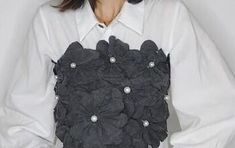 a woman wearing a white shirt with black flowers on the chest and buttons at the back