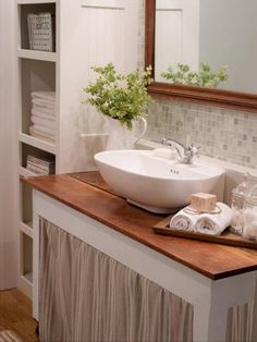 a white sink sitting on top of a wooden counter next to a mirror and shelves