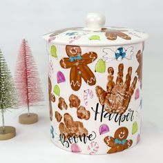 a cookie tin with handprint on it next to a small christmas tree and other decorations