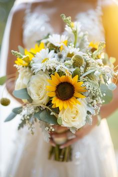 a bride holding a bouquet of sunflowers and greenery