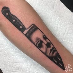 a man's arm with a knife tattoo on it that has an image of a person holding a knife