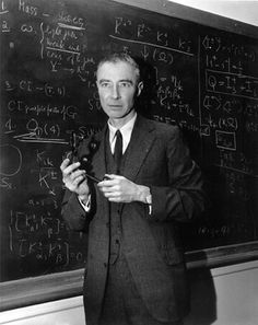 a man standing in front of a blackboard holding something