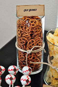 a table topped with lots of pretzels next to a glass filled with candy