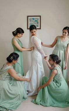 four bridesmaids helping each other put on their dresses