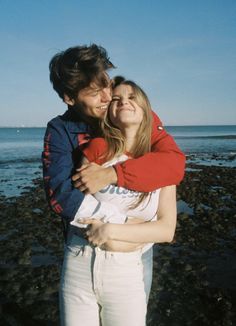 a man and woman hugging each other on the beach