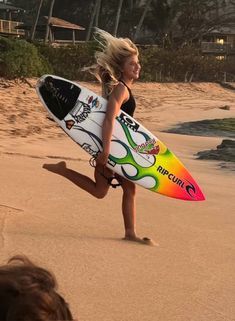 a woman running on the beach with a surfboard in her hand and people watching