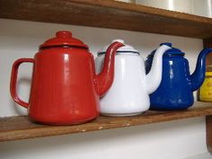 four teapots are lined up on a shelf