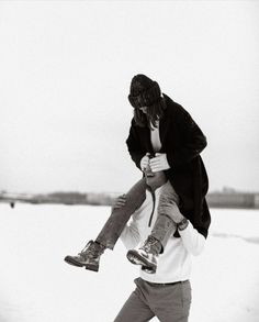 a man carrying a woman on his back in the snow