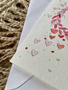 a card with hearts on it sitting next to an envelope