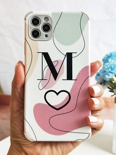 a person holding up a phone case with the letter m on it and a heart