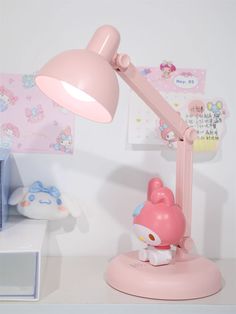 a pink hello kitty lamp sitting on top of a white table next to a wall