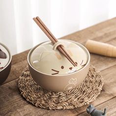 a bowl with chopsticks sticking out of it on a wooden table next to an elephant figurine