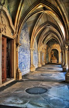 an empty hallway with blue and white graffiti on the walls, arched doorways and columns