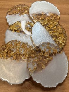 four white and gold leaf shaped dishes sitting on top of a wooden table