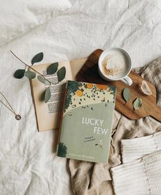 an open book sitting on top of a bed next to a cup and saucer