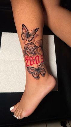 a woman's leg with butterflies and roses on it, which reads 200th