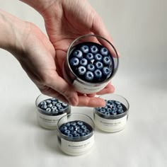 a person is holding some blueberries in small containers