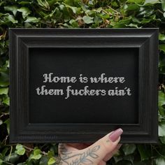 someone is holding up a cross stitch picture frame with the words home is where them fockers are