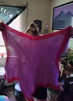 a woman holding up a pink shawl in her living room